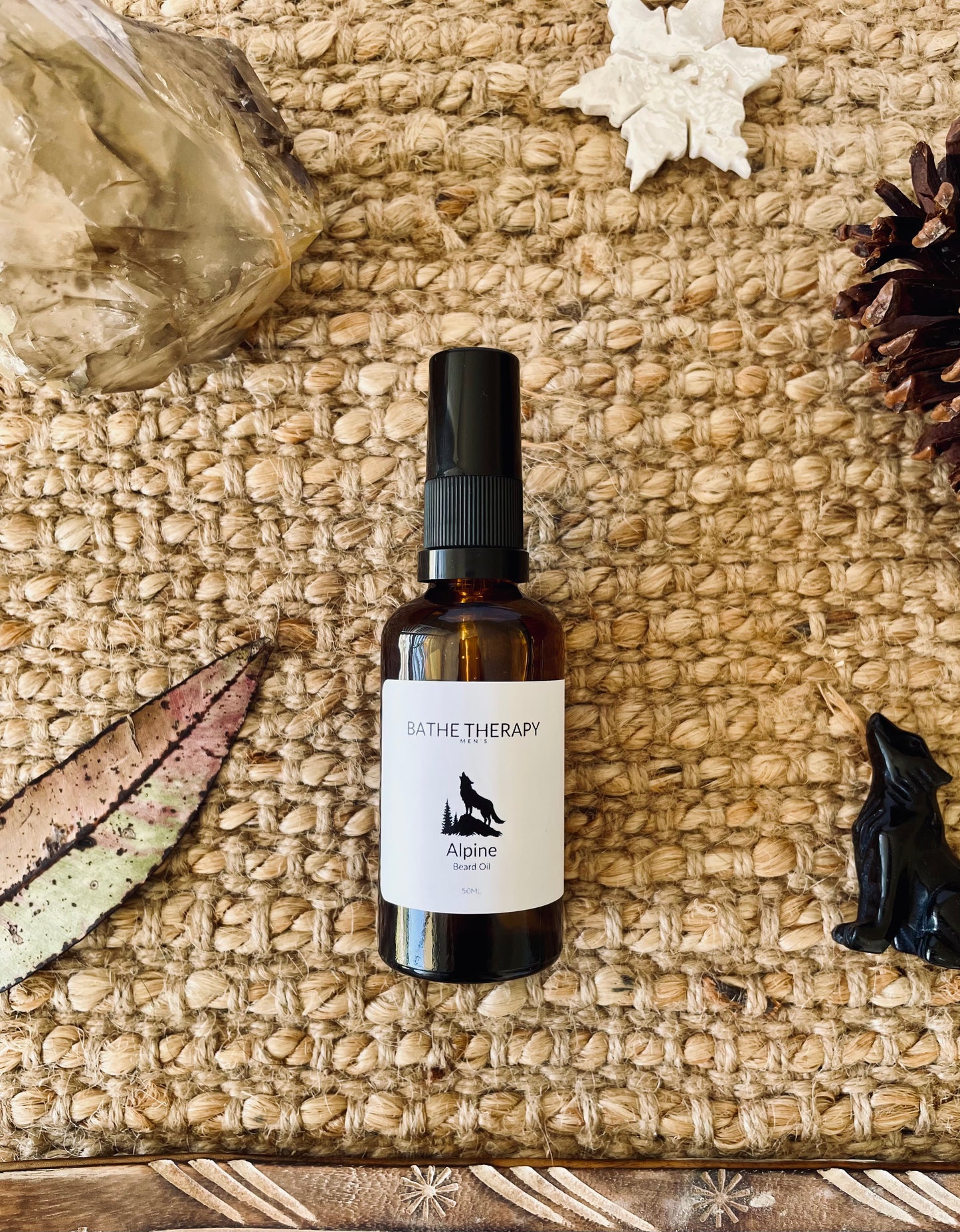 Bottle of 'Bathe Therapy' Alpine Beard Oil on a textured surface with natural elements