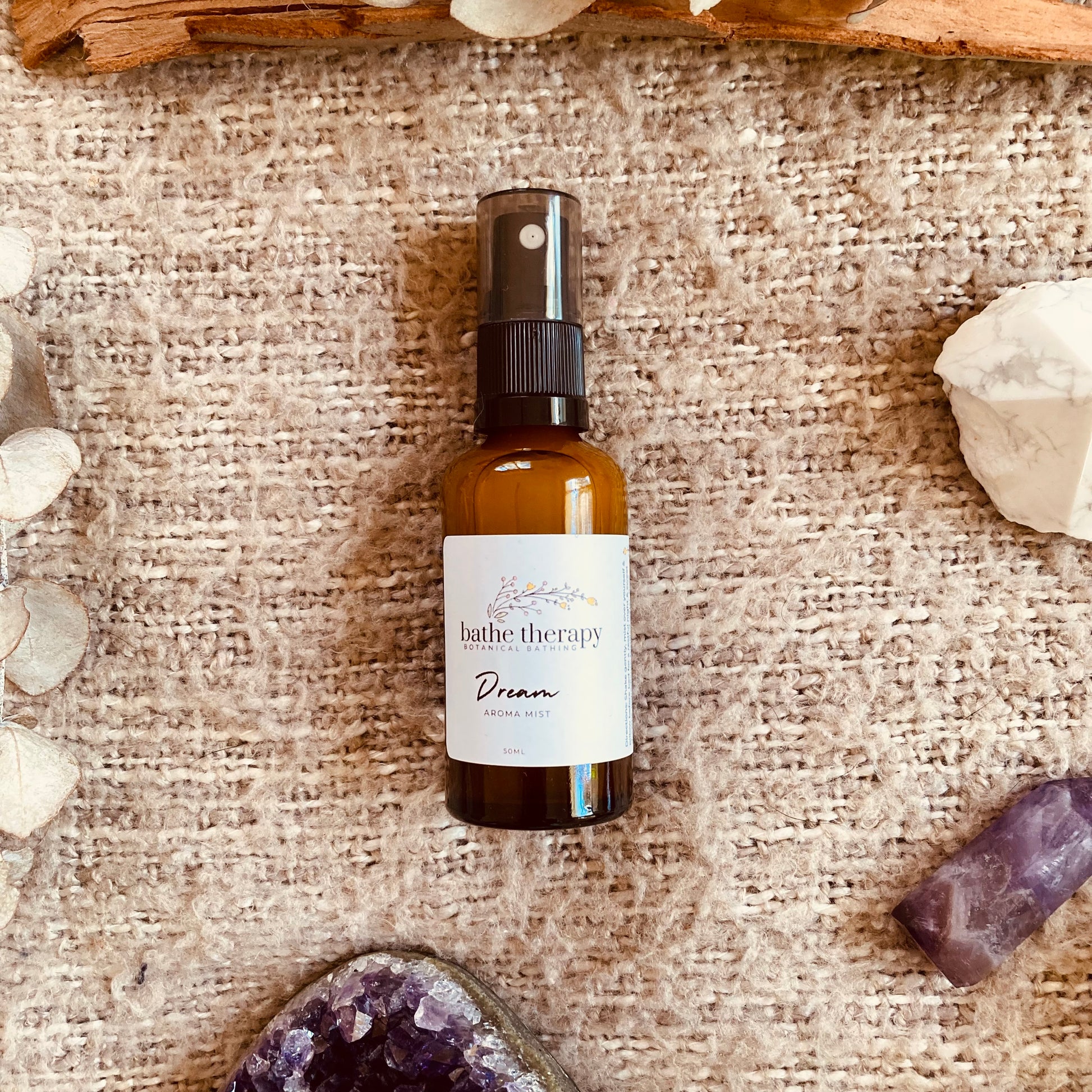 Bottle of dream sleep mist by bathe therapy on textured background with crystals 